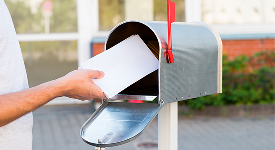 A person is depositing a letter into a mailbox